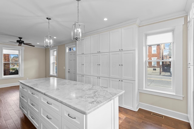 kitchen with crown molding, plenty of natural light, a center island, and white cabinets