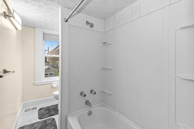 bathroom featuring bathtub / shower combination, toilet, and a textured ceiling