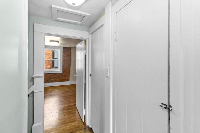 corridor featuring brick wall and dark hardwood / wood-style flooring