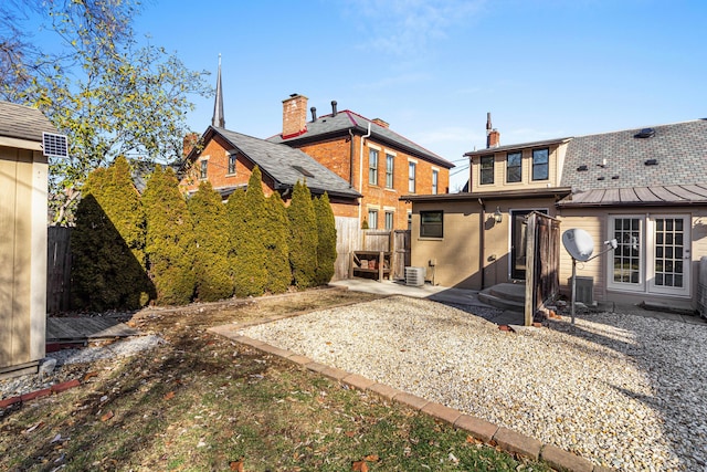 back of property with central AC unit and a patio