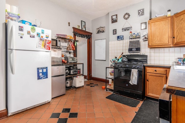 kitchen with tasteful backsplash, black range with gas cooktop, and white fridge