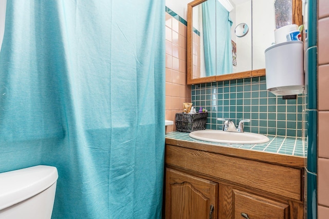 bathroom with vanity, toilet, decorative backsplash, and tile walls