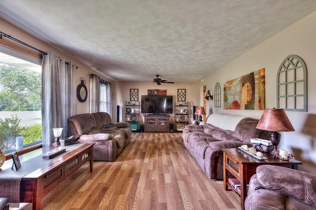 living room with hardwood / wood-style flooring, ceiling fan, and a textured ceiling