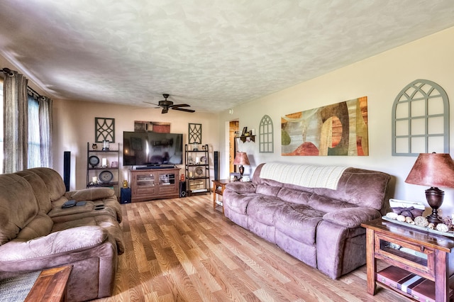 living room with ceiling fan, a textured ceiling, and light hardwood / wood-style flooring