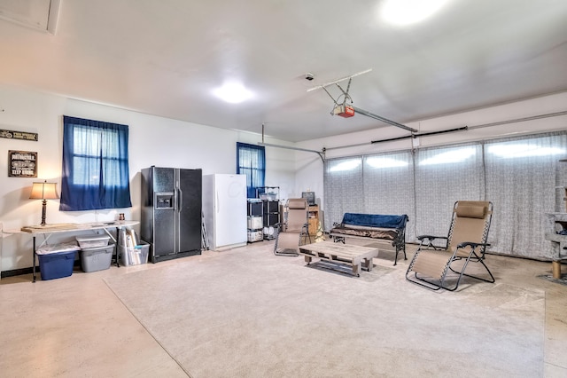 garage featuring black refrigerator with ice dispenser and white refrigerator