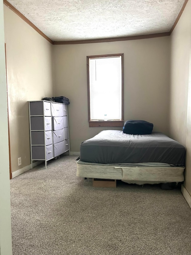 carpeted bedroom with ornamental molding and a textured ceiling