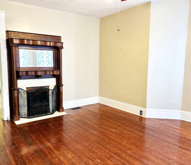 unfurnished living room with a textured ceiling, a fireplace, and wood-type flooring