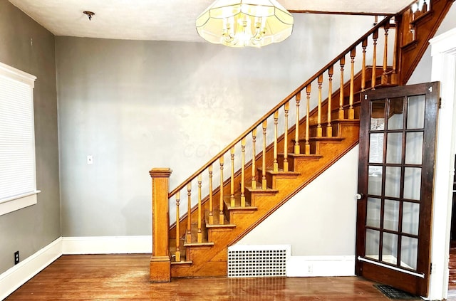 stairs with hardwood / wood-style flooring and a notable chandelier