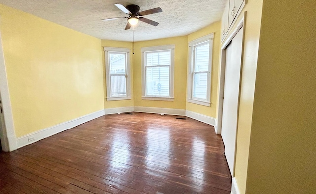 empty room with ceiling fan, dark hardwood / wood-style flooring, and a textured ceiling