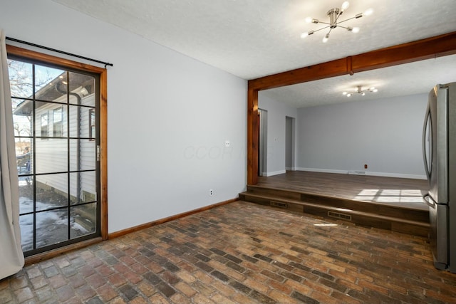 unfurnished room featuring a chandelier, a textured ceiling, and beam ceiling