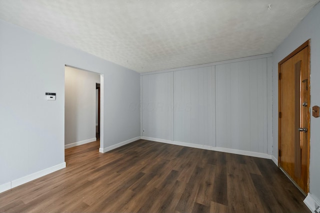 empty room with dark hardwood / wood-style floors and a textured ceiling