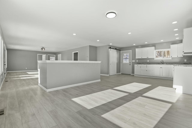 kitchen featuring a kitchen island, white cabinetry, a barn door, and light hardwood / wood-style floors