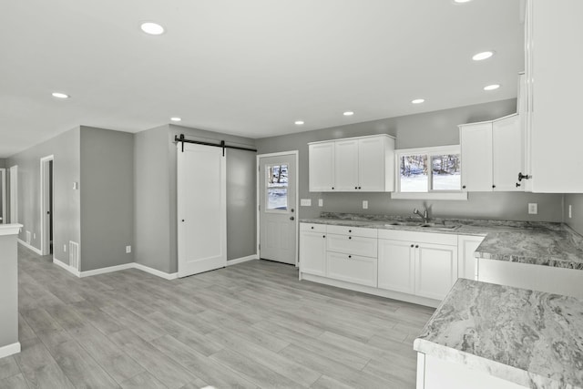 kitchen with white cabinetry, a healthy amount of sunlight, a barn door, and sink