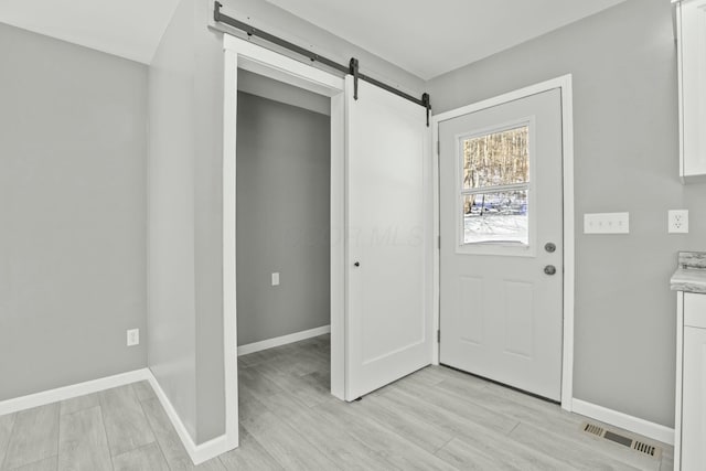 entrance foyer with a barn door and light hardwood / wood-style flooring