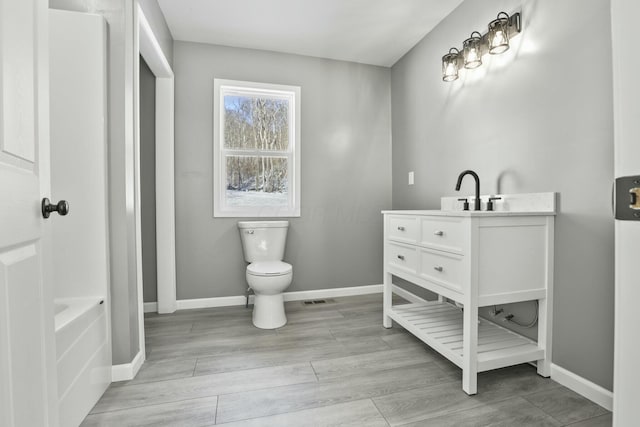 bathroom featuring vanity, wood-type flooring, and toilet