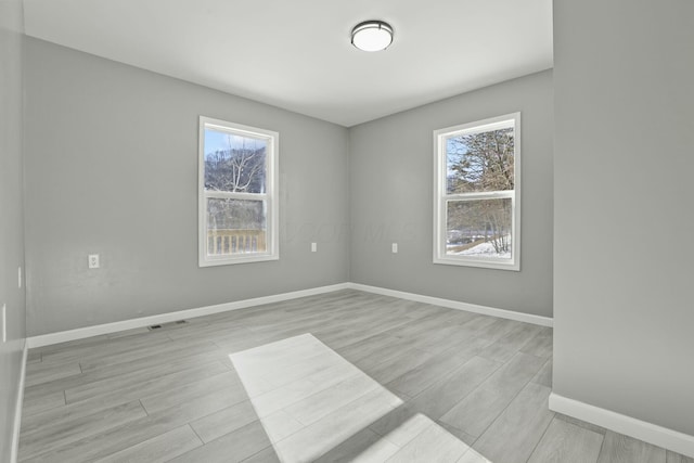 empty room featuring a healthy amount of sunlight and light hardwood / wood-style flooring