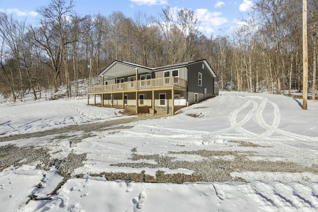 snow covered back of property with a deck