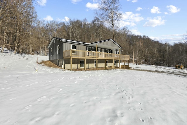 snow covered back of property featuring a deck