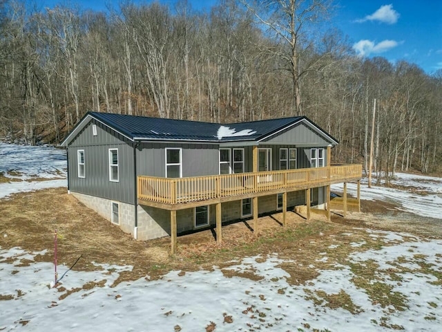 snow covered rear of property with a wooden deck