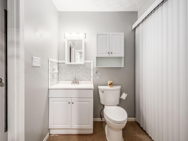 bathroom with tile patterned flooring, backsplash, vanity, and toilet