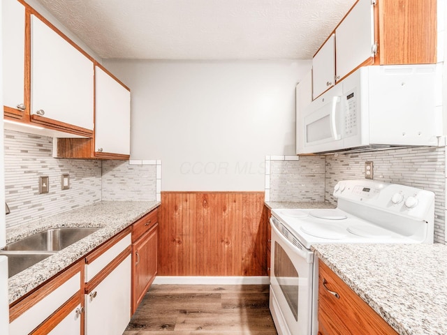 kitchen with white cabinetry, a textured ceiling, white appliances, and light hardwood / wood-style floors