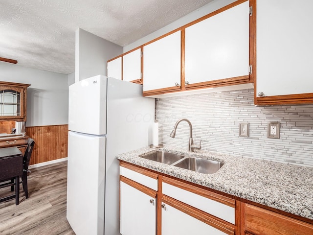 kitchen featuring white cabinetry, sink, fridge, a textured ceiling, and light hardwood / wood-style flooring