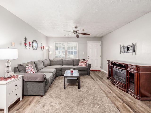 living room with ceiling fan, light hardwood / wood-style flooring, and a textured ceiling