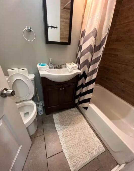 full bathroom featuring tile patterned floors, vanity, toilet, and shower / bath combo with shower curtain