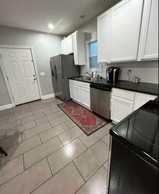 kitchen with sink, light tile patterned floors, stainless steel appliances, and white cabinets