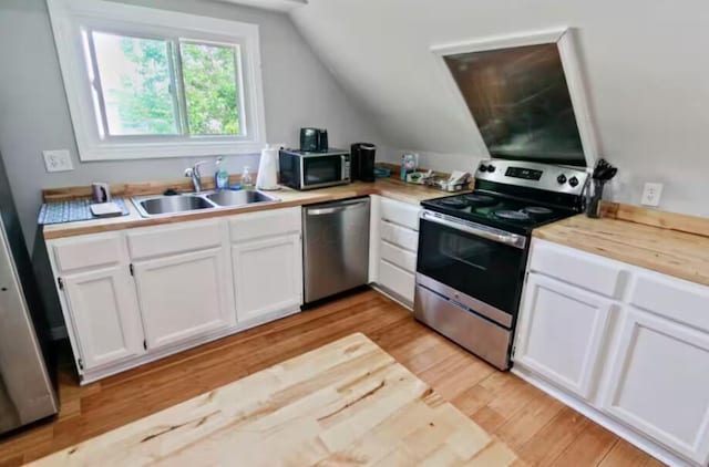 kitchen with lofted ceiling, sink, light hardwood / wood-style flooring, stainless steel appliances, and white cabinets