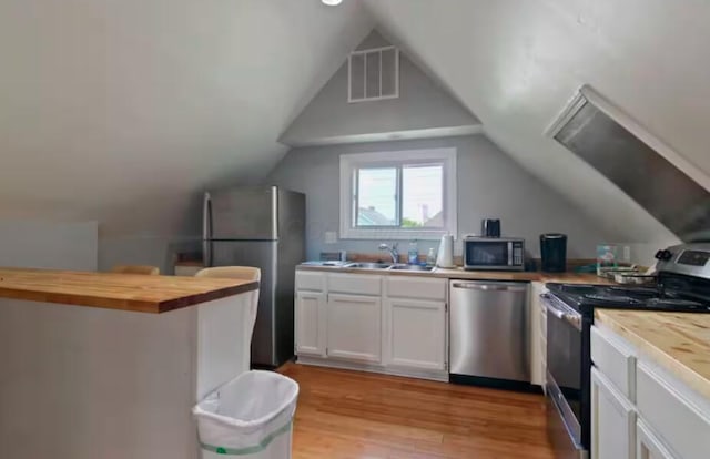 kitchen with sink, white cabinetry, wooden counters, appliances with stainless steel finishes, and light hardwood / wood-style floors