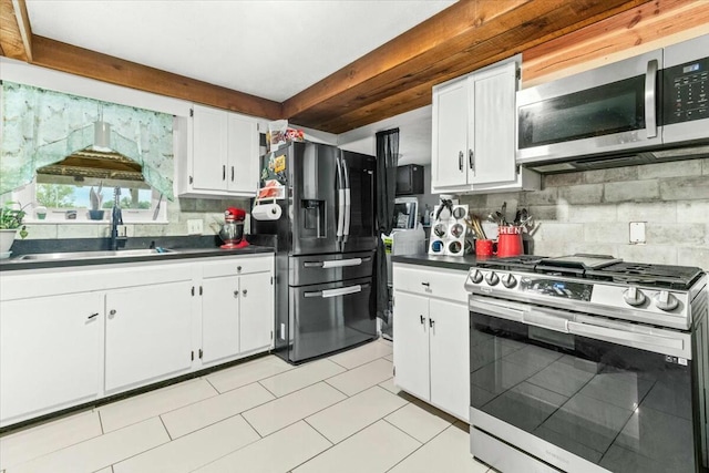 kitchen with sink, white cabinetry, light tile patterned floors, stainless steel appliances, and decorative backsplash