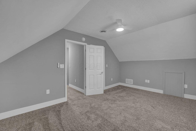 additional living space with lofted ceiling, a textured ceiling, light carpet, and ceiling fan