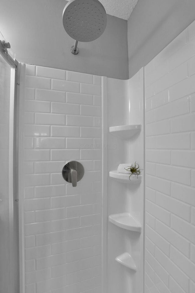 interior details with a tile shower and a textured ceiling