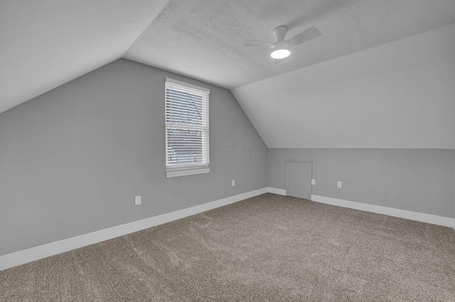 additional living space featuring ceiling fan, carpet flooring, vaulted ceiling, and a textured ceiling