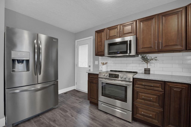 kitchen featuring stainless steel appliances, light stone countertops, a textured ceiling, dark hardwood / wood-style flooring, and decorative backsplash