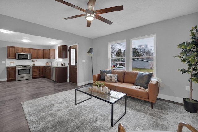 living room with sink, a textured ceiling, dark wood-type flooring, and ceiling fan