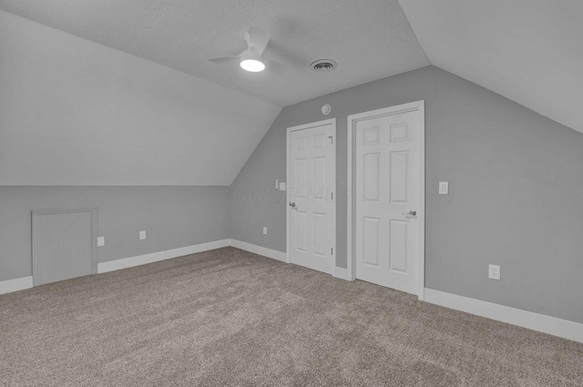 additional living space featuring ceiling fan, lofted ceiling, carpet, and a textured ceiling