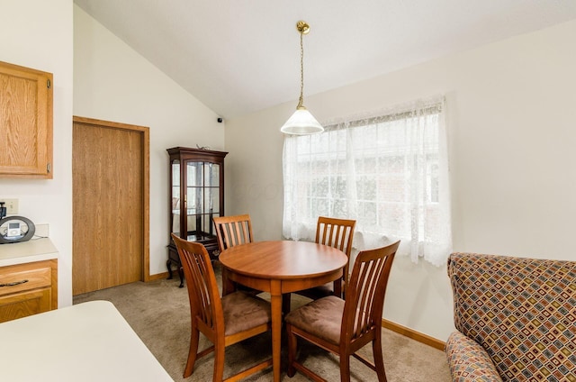 carpeted dining room with lofted ceiling