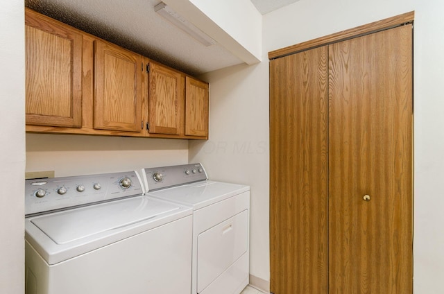 clothes washing area with washing machine and dryer and cabinets