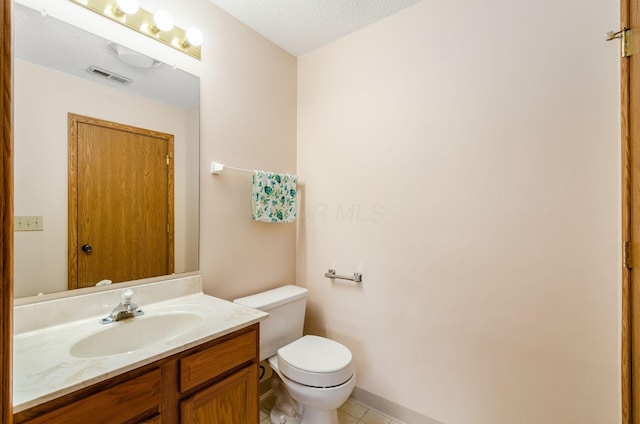 bathroom with tile patterned flooring, vanity, a textured ceiling, and toilet