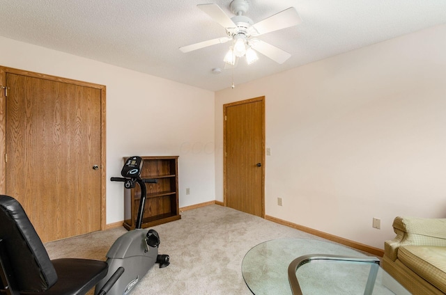 workout area featuring ceiling fan, light carpet, and a textured ceiling