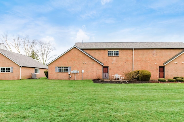 back of property featuring a yard and central AC