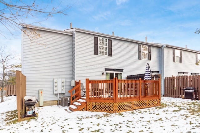 snow covered back of property featuring central AC and a deck