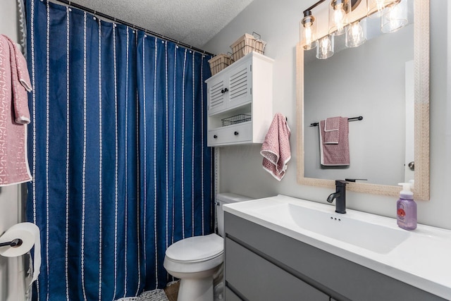 bathroom with vanity, toilet, and a textured ceiling