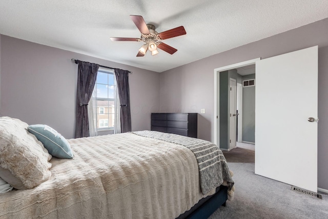 carpeted bedroom featuring ceiling fan and a textured ceiling