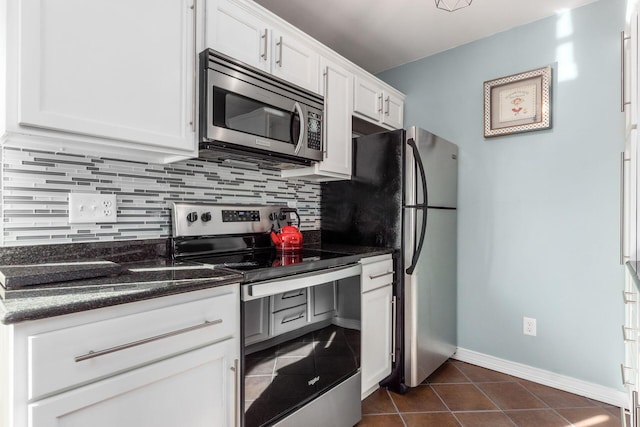 kitchen featuring tasteful backsplash, dark stone countertops, appliances with stainless steel finishes, dark tile patterned flooring, and white cabinets