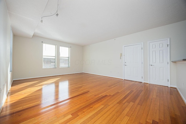 empty room with a textured ceiling and light wood-type flooring