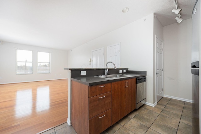 kitchen featuring sink, track lighting, dishwasher, kitchen peninsula, and hardwood / wood-style flooring