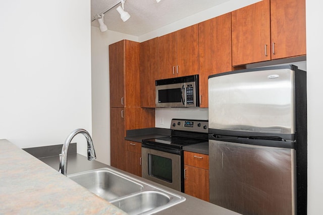 kitchen featuring stainless steel appliances, rail lighting, sink, and a textured ceiling